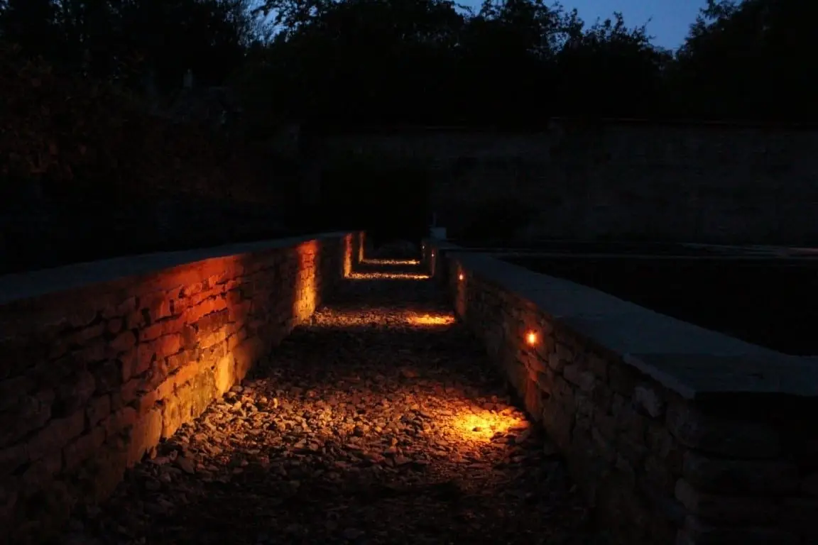 Evening view of the Hartley Botanic greenhouse and walled garden lit by warm white wall lights